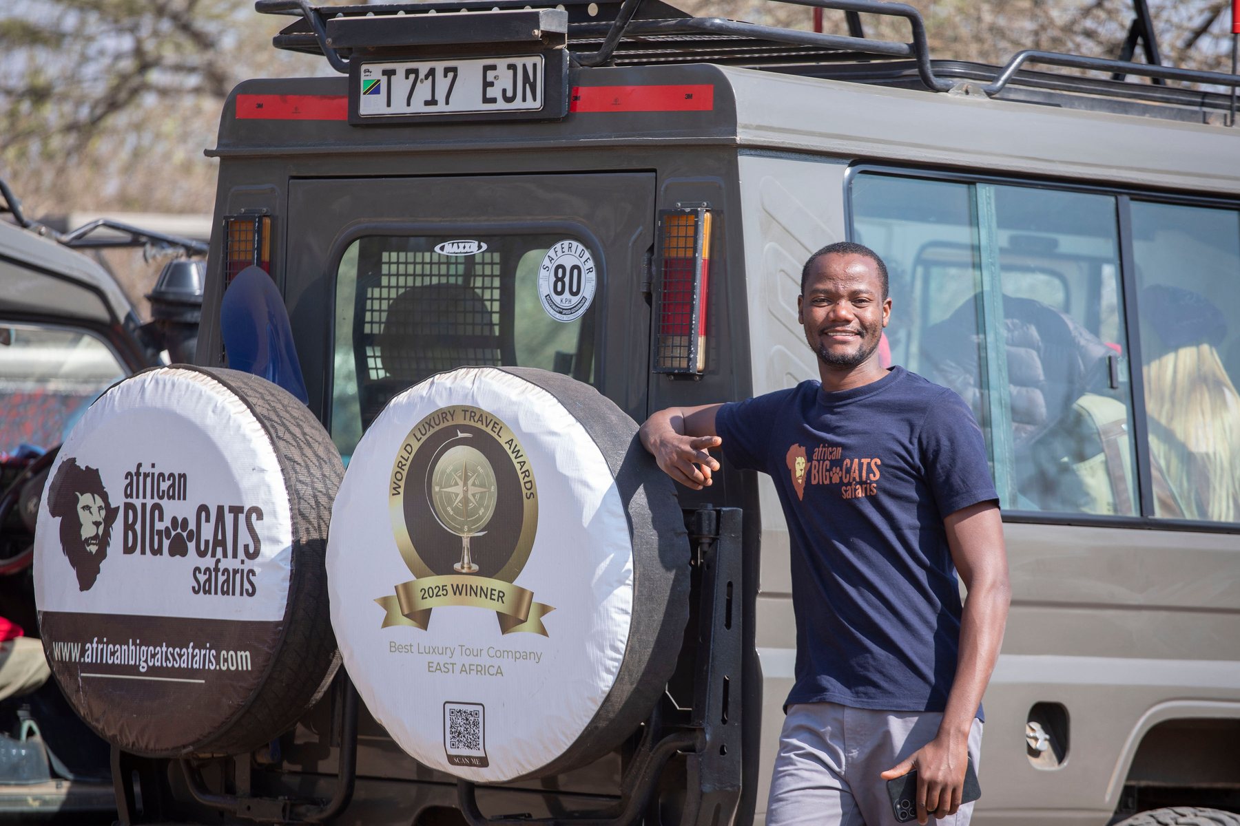 African Big Cats Safaris guide beside a safari vehicle carrying the 2025 World Luxury Travel Awards winner badge